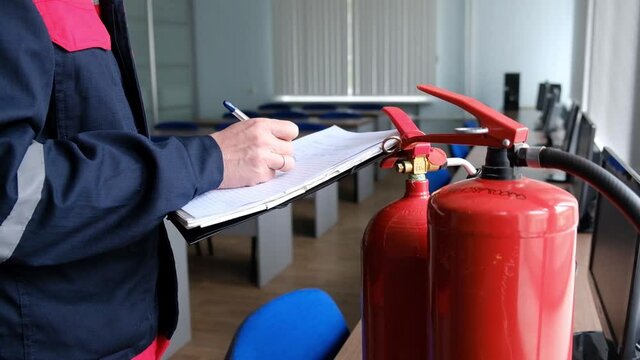 Engineer Professional are Checking A Fire Extinguisher and writes data to the check log. Fire Alarm controller.System ready In the event of a fire.