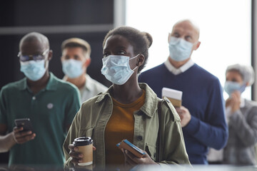 Group of people in protective masks holding tickets and waiting for the departure at the airport - obrazy, fototapety, plakaty