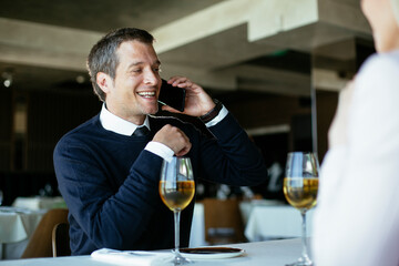 Handsome businessman dressed in the suit drinking wine. Businessman talking to the phone...
