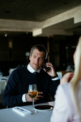Handsome businessman dressed in the suit drinking wine. Businessman talking to the phone...