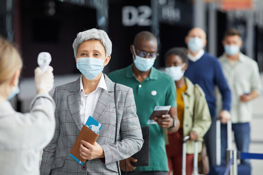 Group of people in mask standing in a row and testing they are at the airport