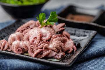 Traditional japanese or seafood concept. Delicious and healthy boiled mini octopus and wakame or seaweed salad with soy sauce and lemon served with chopstick.