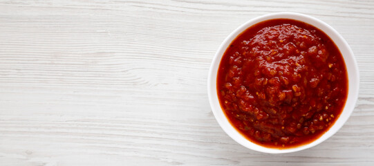 Obraz na płótnie Canvas Homemade Tomato Salsa on a white wooden background, top view. Flat lay, overhead, from above. Copy space.