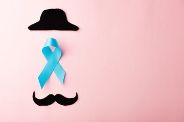 Black mustache paper and light blue ribbon, studio shot isolated on pink background, Prostate cancer awareness month, Fathers day, minimal November moustache concept