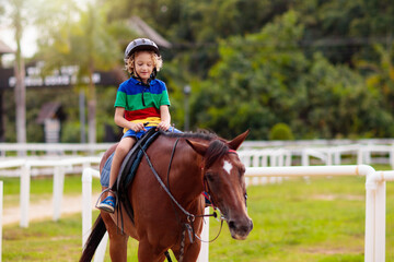 Kids ride horse. Child on pony. Horseback riding.