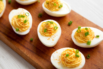 Homemade Deviled Eggs with Chives on a rustic wooden board on a white wooden background, low angle view. Close-up.
