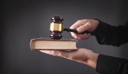 Lawyer or judge holding gavel and book.