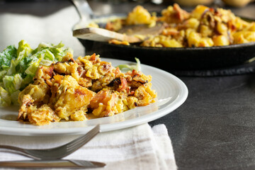 fried potatoes with eggs, ham, bacon and onion on plate ready to eat