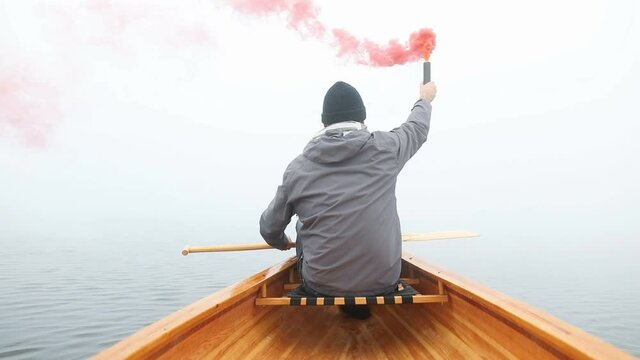 Canoeist using smoke bomb to signal his position on the foggy lake