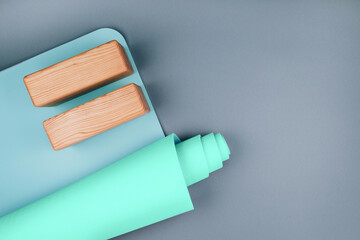 Top view of blue green yoga mat and two wooden blocks on pastel grey background. Yoga pilates Sport concept. Flat Lay. Copy space.