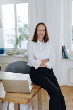Smiling businesswoman perched on an office table