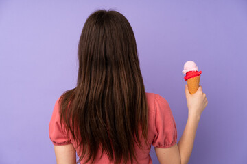 Young Ukrainian teenager girl holding a cornet ice cream over isolated purple background in back position