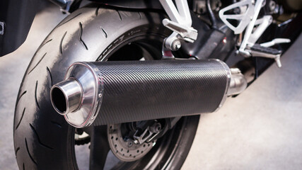 Back of modern sports bike, bottom side view, close-up. Carbon exhaust pipe, brake disc, alloy...