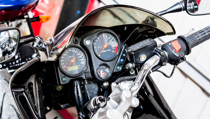 Fototapeta na wymiar View of steering wheel of modern sports motorcycle. Pointer speedometer, tachometer with keyhole and motorcycle keys closeup in garage. Dashboard with throttle grips road bike and tank, top view