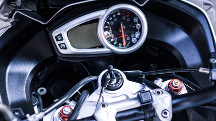 Steering wheel of sport bike. Modern electronic speedometer and pointer tachometer with indicators and keyhole, keys to motorcycle on handlebars close-up. Dashboard of road motorcycle, top view