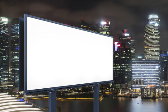 Blank White Road Billboard With Singapore Cityscape Background At Night Time. Street Advertising Poster, Mock Up, 3D Rendering. Side View. The Concept Of Marketing Communication To Sell Idea.