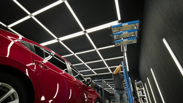 Red lamps for drying the ceramic coating are behind car