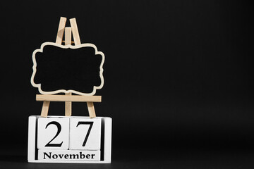 The calendar is November 27, and the frame on the stand on a black background, the concept layout to Black Friday. Copy space.