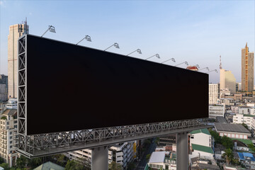 Blank black road billboard with Bangkok cityscape background at day time. Street advertising poster, mock up, 3D rendering. Side view. The concept of marketing communication to promote or sell idea.
