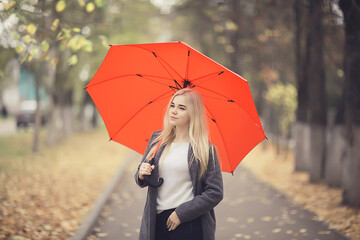 Obraz premium girl with umbrella posing in autumn park, october landscape lonely woman holding a red umbrella