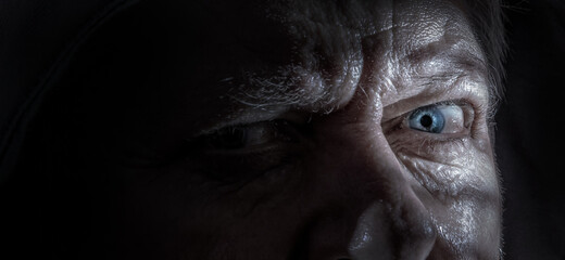 Detail of a portrait of an elderly man. He has an intense, evil look.