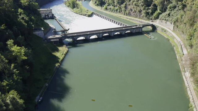 Aerial view of an historic hydroelectric power plant located on a river bank, which exploits the difference in height created by the dam on the Adda river, Italy