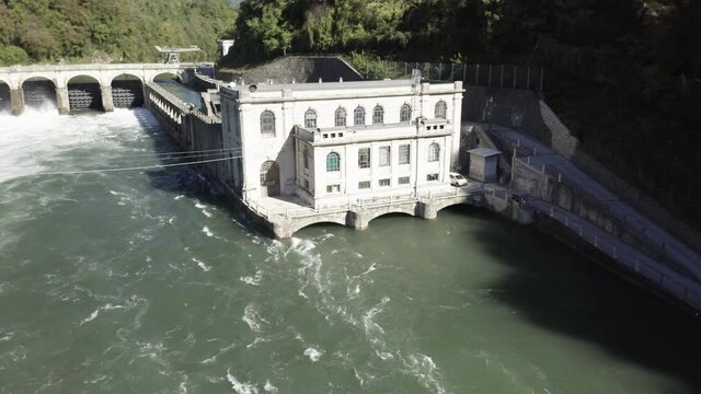 Aerial view of an historic hydroelectric power plant located on a river bank, which exploits the difference in height created by the dam on the Adda river, Italy