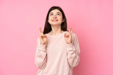 Young Ukrainian teenager girl over isolated pink background with fingers crossing and wishing the best