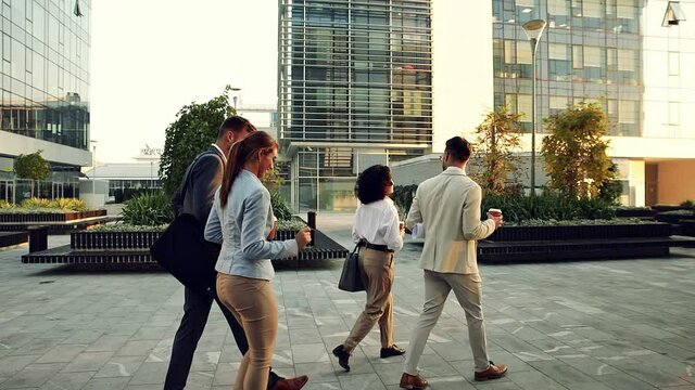 Group of business people walking outside in front of office buildings.