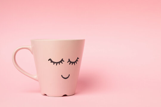 Cup with happy face on pink background