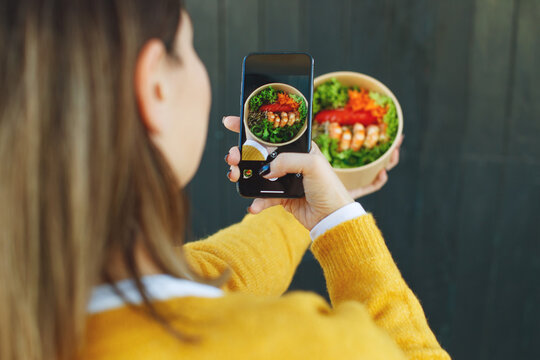 A woman photographs food on her phone. High quality photo.