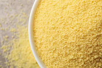 Bowl with raw couscous on gray background