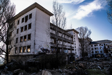Edificio de antiguo sanatorio en ruinas con árboles sin hojas - obrazy, fototapety, plakaty