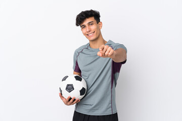 Young Argentinian man over isolated white background with soccer ball and pointing to the front