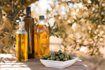 green olives and oil on table in olive grove