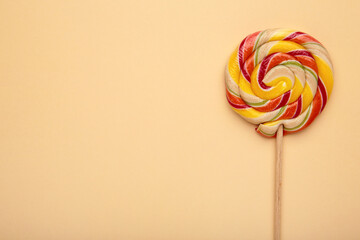 Multicolored lollipop on beige background, view from above. copy space.