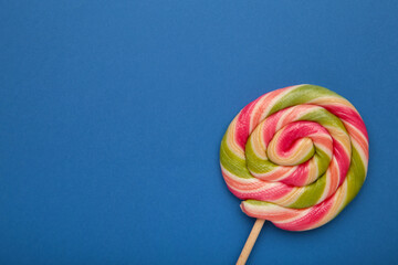 Multicolored lollipop on blue background, view from above. copy space.