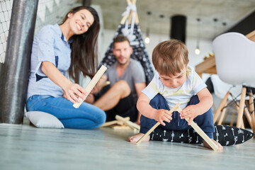 Parents help child pile wood for campfire