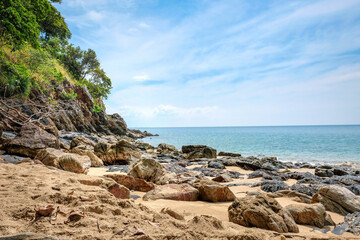 Fototapeta na wymiar Beautiful rocky beach. Coast with tropical greenery. Turquoise sea and blue sky with clouds