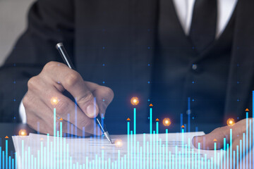 Businessman in suit signs contract. Double exposure with financial chart hologram. Man signing mortgage agreement. Real estate market analysis and investment concept.