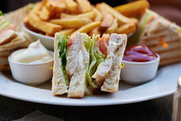 klassischer Clubsandwich Toast mit Huhn Pute Salat und als Beilage Pommes mit Ketchup und Mayonnaise 
