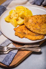 Chop pork cutlets , served with boiled potatoes and salad of pickled cucumbers on wooden board. A typical Polish dinner (kotlet schabowy).

