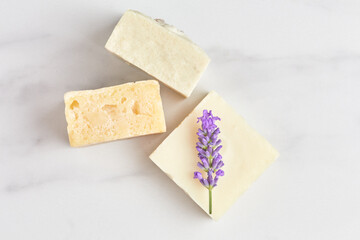 stack of hand-made soap, decorated with a fresh lavender branch on a marble background. flat lay, top view