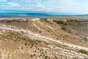 View from the height of the white rock and green valley. Blue sky, a small village at the bottom. Crimea