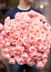 Young man with a gift bouquet of spray roses, mono bouquet of roses. Young man holding fresh...