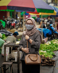 Muslim women wearing health cloth masks while in traditional markets shopping for vegetables.