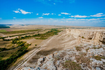 View from the height of the white rock and green valley. Blue sky, a small village at the bottom. Crimea