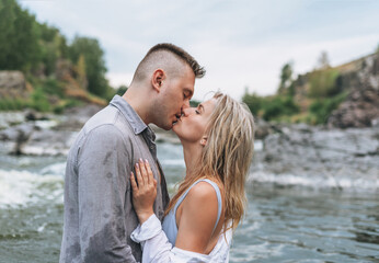 Happy young couple in love travelers kissing in the mountain river