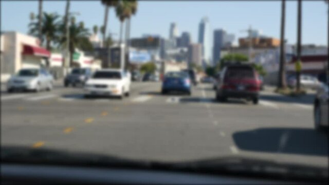 Driving on downtown streets of Los Angeles, California USA. Defocused view from car thru glass windshield on driveway. Blurred road with vehicles in Hollywood. Camera inside auto, LA city aesthetic.