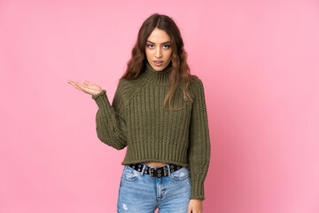 Young woman over isolated pink background making doubts gesture